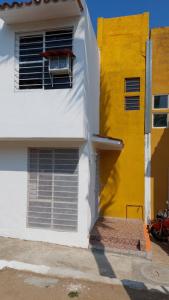 un bâtiment jaune et blanc avec une chaise dans la fenêtre dans l'établissement RELAJACION SERCAS DEL AEROPUERTO, 