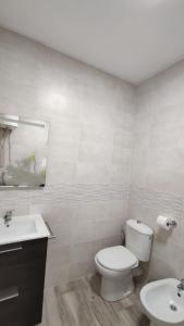 a white bathroom with a toilet and a sink at Apartamento en Costacabana in El Alquián