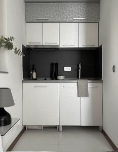 a kitchen with white cabinets and a black wall at Apartments Villa Stefan in Budva