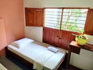 Habitación pequeña con cama y ventana en Hostal Casa La Candelaria, en Mompós