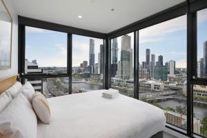 um quarto com uma cama branca e vista para a cidade em The Canvas Apartment Hotel em Melbourne
