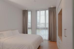 a white bedroom with a bed and a large window at Residencias Cityzen cerca del Aeropuerto in Echeverría