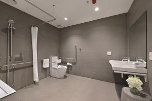 a bathroom with a toilet and a sink and a shower at The Canvas Apartment Hotel in Melbourne