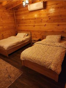 2 camas en una habitación con paredes de madera en منتجع أكواخ گيفأ, en Tabuk
