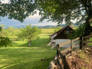 a barn in a field next to a fence at La Prairie in Korenica