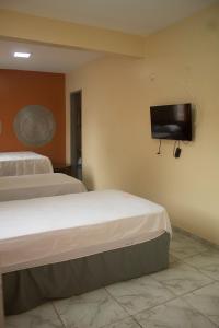 a bedroom with two beds and a flat screen tv on the wall at Hotel Itatiaia in São Luís