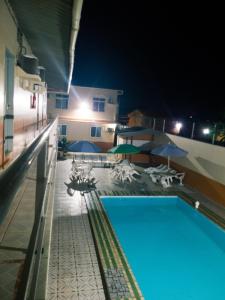 a swimming pool at night with umbrellas and chairs at Hotel Itatiaia in São Luís