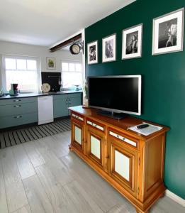 uma sala de estar com uma televisão de ecrã plano numa parede verde em Kunst und Meer em Varel
