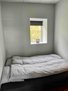 Cama en habitación blanca con ventana en Pauli’s Boathouse, en Vestmanna