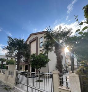 a house with a fence and palm trees in front of it at Apartments Villa Stefan in Budva