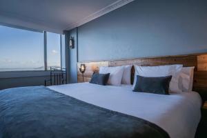 1 dormitorio con 1 cama blanca grande y ventana grande en Gran Hotel Versalles Puerto Montt, en Puerto Montt