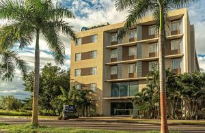 a building with palm trees in front of it at Best Western Puerto Gaitan in Puerto Gaitán