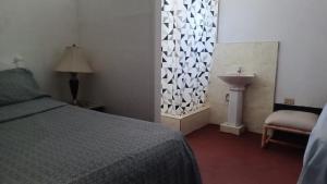 a bedroom with a bed and a sink and a window at Drifters@One Mile in Negril