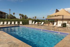 a swimming pool with chairs and umbrellas at Hale Kamaole in Wailea