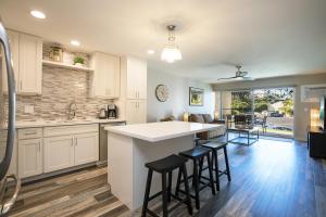 a kitchen with white cabinets and a island with bar stools at 126 Hale Kamaole in Wailea