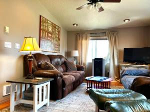 sala de estar con sofá de cuero y TV en Sage Oasis Garden Retreat en Hot Springs