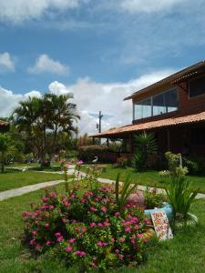 a garden with pink flowers in front of a building at Chácara da Bel in Pitimbu