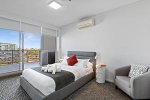 a bedroom with a bed and a chair and a window at AAN Apartments North Sydney in Sydney