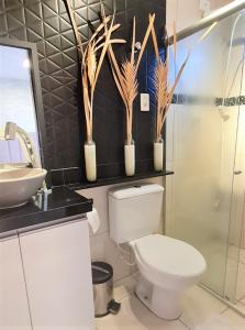 a bathroom with a toilet and a sink and plants at Flat Paraíso em Serra Negra- Bezerros/PE in Bezerros