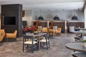 a waiting room with tables and chairs and a tv at Courtyard by Marriott Minneapolis West in Saint Louis Park