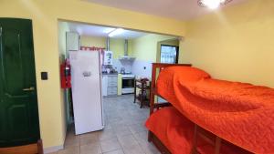 una cocina con nevera y una cama roja en una habitación en El Aromito en Alta Gracia
