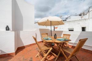 una mesa de madera y sillas con una sombrilla en el techo en Preciosa casa independiente con increibles vistas, en Vejer de la Frontera