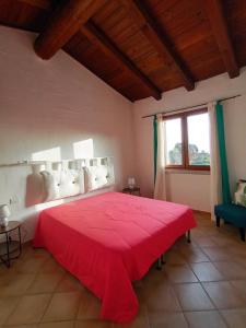 a bedroom with a red bed and a window at Il Miraggio Tanca Piras in Nebida