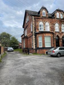 una casa di mattoni con due macchine parcheggiate di fronte di The Crescent, Flat 1 - Stockport, Manchester a Manchester