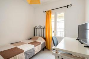 Un dormitorio con una cama, un escritorio y un televisor. en Preciosa casa independiente con increibles vistas, en Vejer de la Frontera