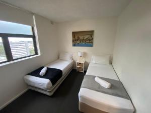 two beds in a small room with a window at Surfers Private Apartments in Gold Coast
