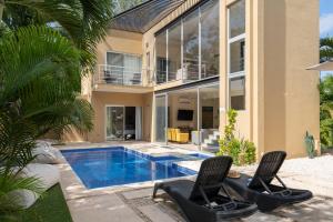 a house with a swimming pool and two chairs at Tulum Private Modern Villa-Pool Beds-AC-Internet-Parking-Grill in Tulum