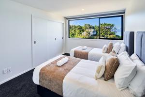 two beds in a room with a large window at Brand New Townhouse with Ocean Views in Wellington