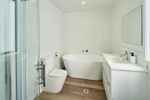 een badkamer met een bad, een toilet en een wastafel bij Brand New Townhouse with Ocean Views in Wellington