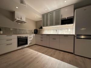 a large kitchen with white cabinets and stainless steel appliances at Beautiful view, perfect place to see northern lights! in Tromsø