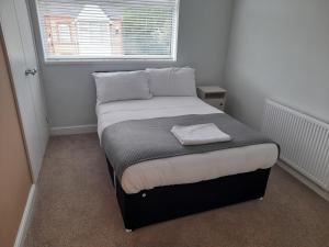 - un petit lit dans une chambre avec fenêtre dans l'établissement Chorlton Apartments, à Sale