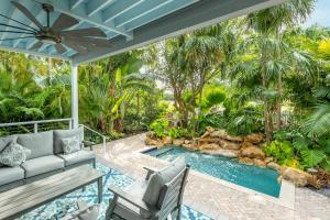 an outdoor patio with a pool and a couch and chairs at Tropical Retreat in Key West