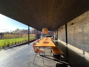 - une longue table en bois avec des chaises sur la terrasse dans l'établissement Bigaro II, à Heers