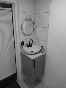 a bathroom with a sink and a mirror at Samm's Studio Apartment in Hyde Park