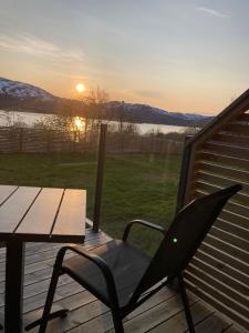 a table and a chair on a deck with the sunset at Beautiful view, perfect place to see northern lights! in Tromsø