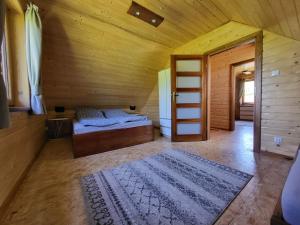 a bedroom with a bed in a wooden room with two rugs at Agroturystyka Pod Lipą in Małe Leżno