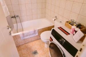 a bathroom with a tub and a toilet and a washing machine at Morpheus Realm Apartment in Ioannina