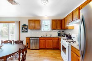 eine Küche mit Holzschränken, einem Tisch und einem Herd in der Unterkunft Hyannis Beach House in Hyannis