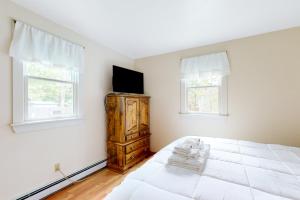 um quarto com uma cama branca e uma televisão numa cómoda em Hyannis Beach House em Hyannis