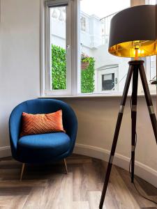 a blue chair and a lamp in a room with a window at Liam's Place near Hyde Park in London