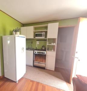 een keuken met een witte koelkast en een magnetron bij Cabañas Portal del Rio in Nahuentúe