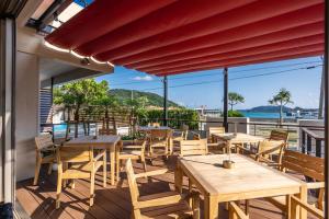 un ristorante con tavoli e sedie in legno su un balcone di サンメール座間味 a Zamami