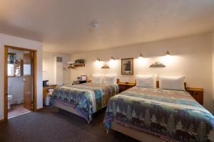 ein Hotelzimmer mit zwei Betten und einem Spiegel in der Unterkunft Elk Horn Lodge in Cooke City