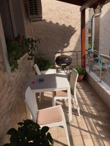 una mesa blanca y sillas en un patio con parrilla en Nikos Apartament en Prinos