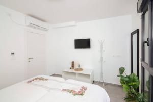 a white bedroom with a bed and a tv on the wall at Agrippas Suite 6 in Jerusalem