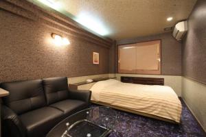 a bedroom with a bed and a couch and a table at HOTEL Iz bayside 大人専用 in Funabashi